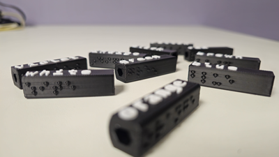 An image of 9 black and white crayon caps that have braille and print on them to help distinguish color.